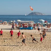 Rio de Janeiro, Brazil - January 22, 2014: Four men play footvolley in Ipanema Beach in a beautifull and hot summer afternoon. Sunbathers relax (background).
